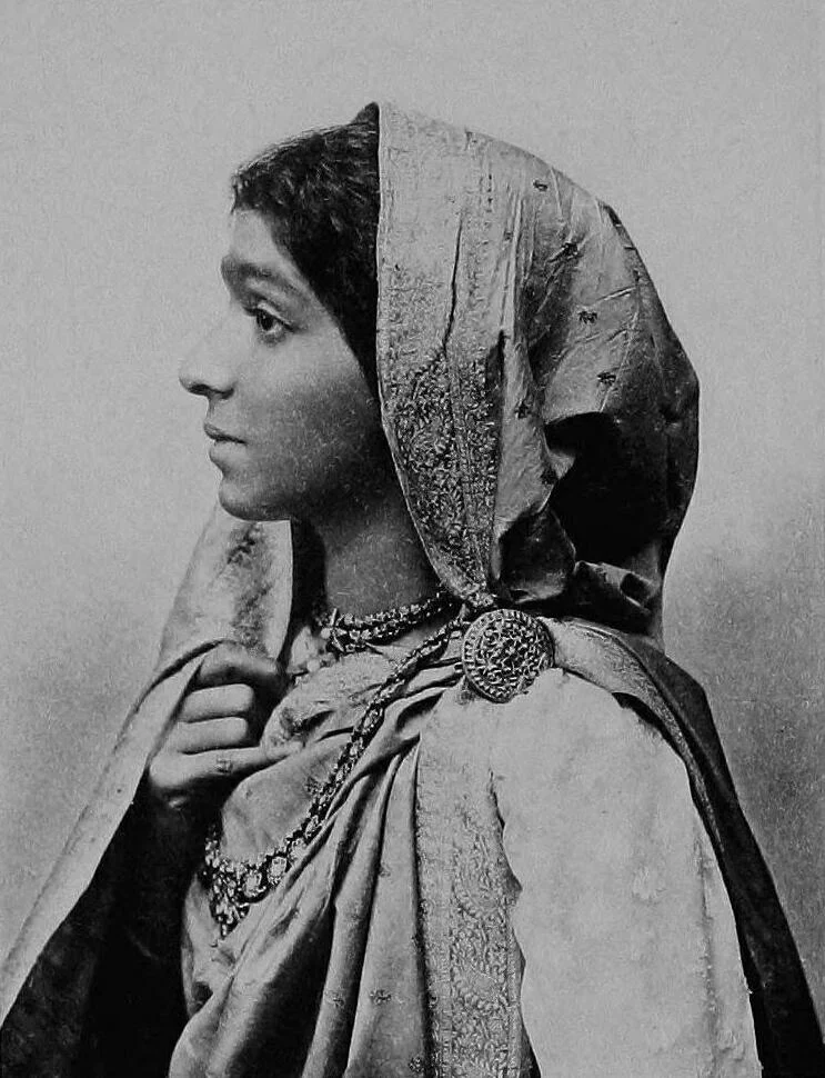 Sarojini Naidu in profile, wearing a sari draped over her head