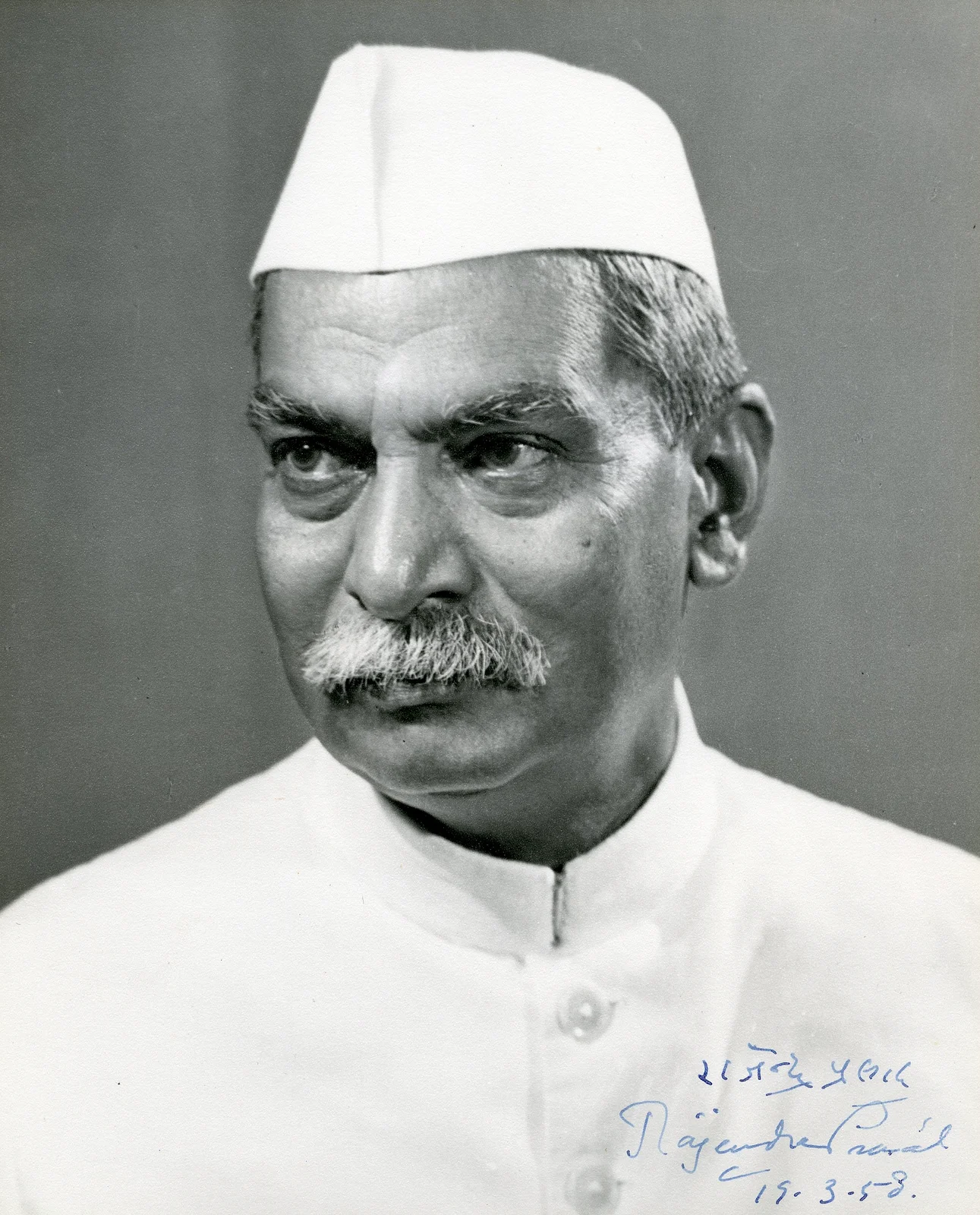 Rajendra Prasad in a white cap, looking to one side