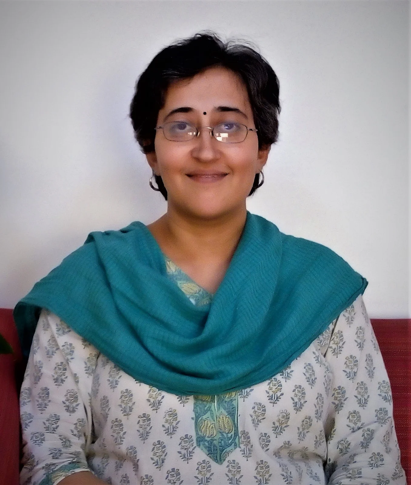Atishi in spectacles and a teal scarf, smiling