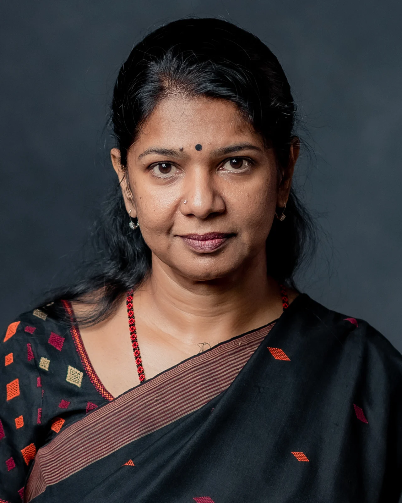 Kanimozhi Karunanidhi in a dark sari, smiling at the camera