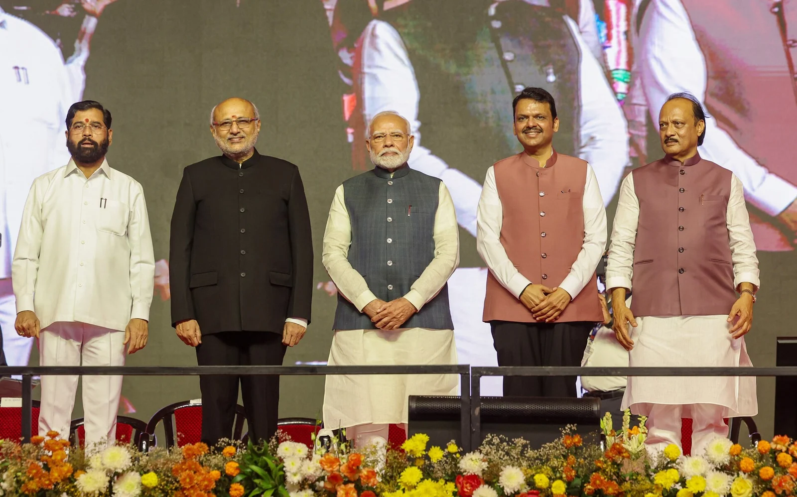 Leaders standing on a stage at a swearing-in ceremony in Mumbai